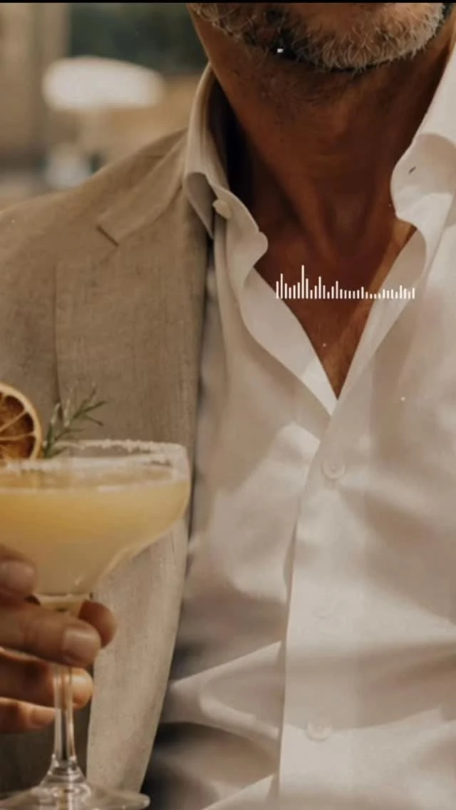 Americana de lino y camisa blanca, con un cóctel en la mano