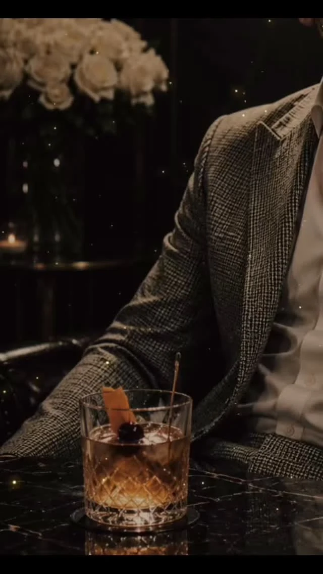 Americana de tweed y un cóctel con piel de naranja sobre una mesa de mármol