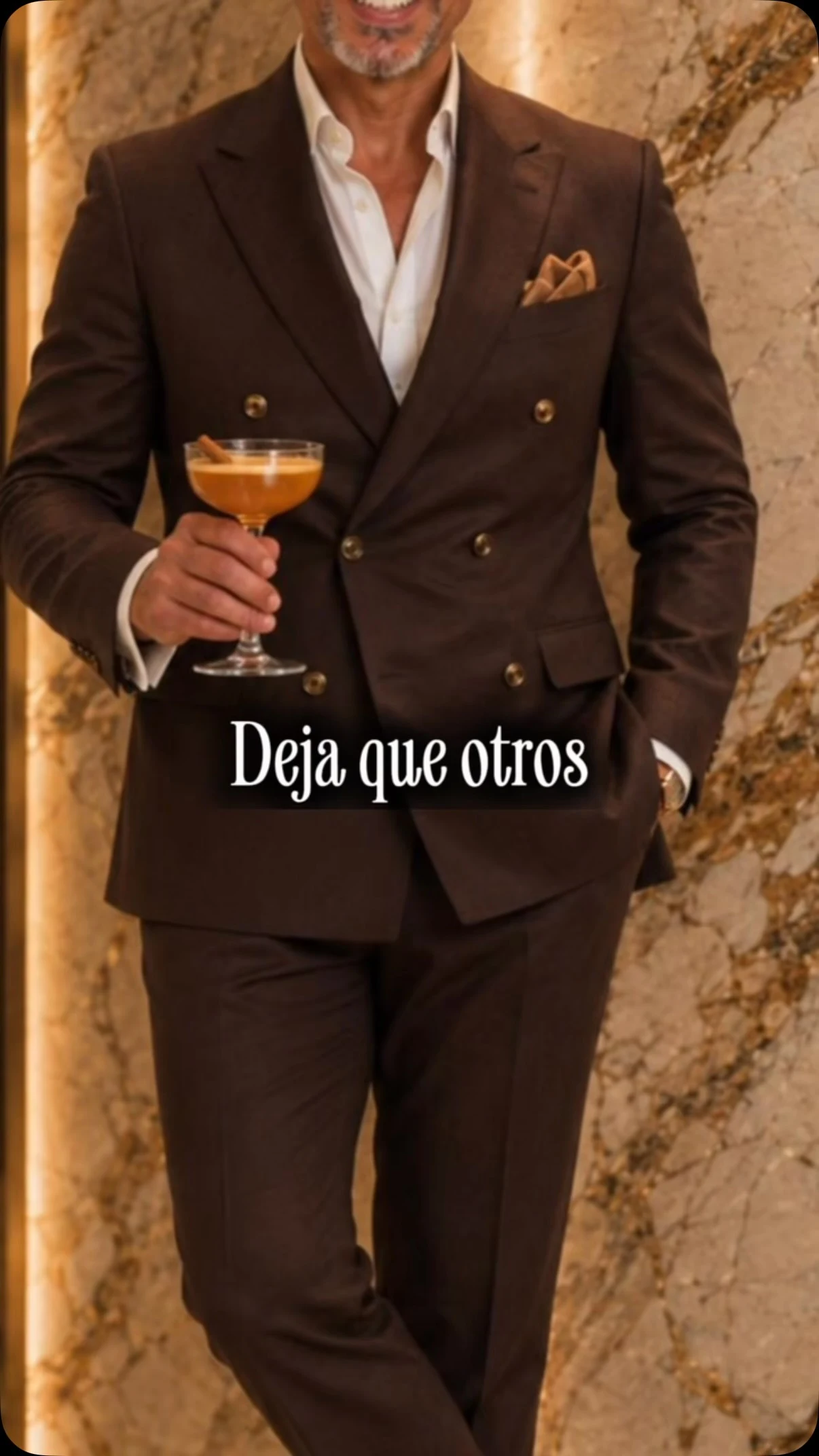 Traje marrón cruzado y camisa blanca, con un cóctel en la mano